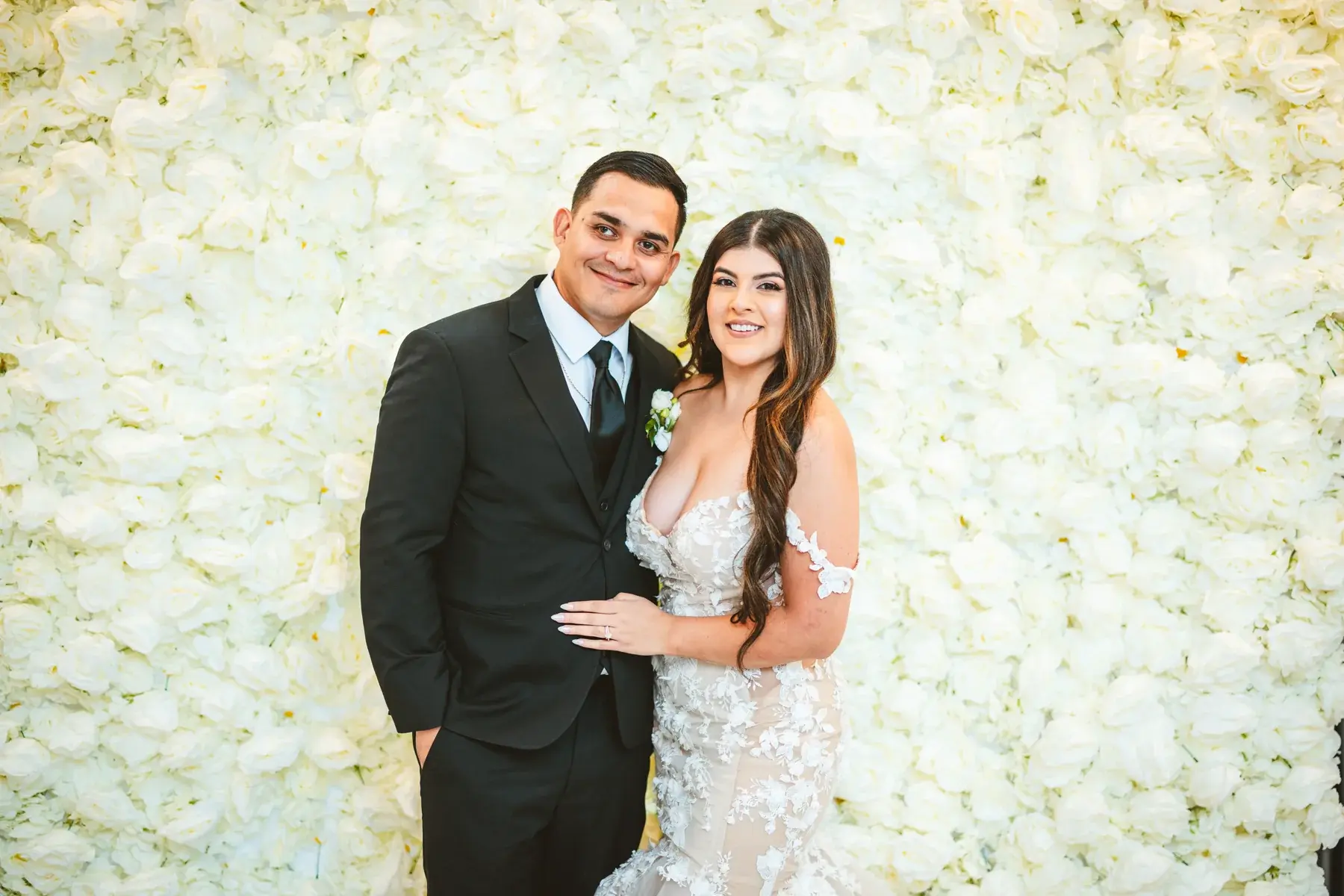 Our wedding portrait against the white rose wall