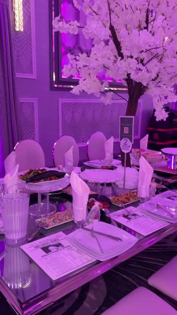 White cherry blossom tree beside wedding reception dining tables under purple event lighting